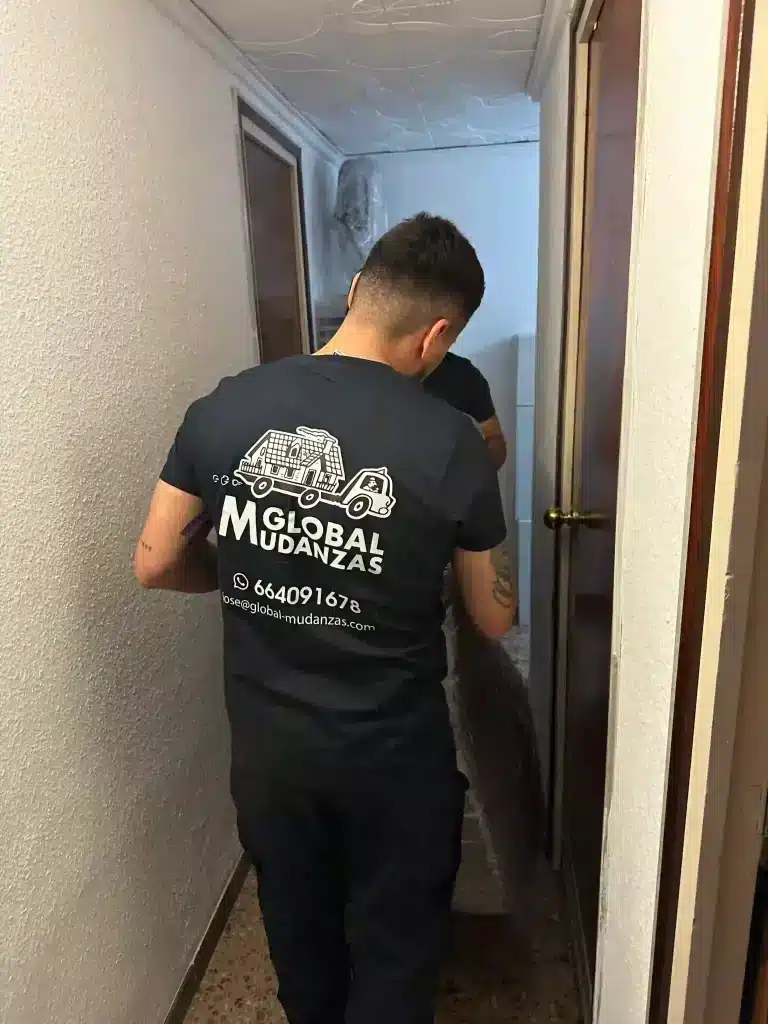 Operario de Global Mudanzas trasladando un mueble protegido por un pasillo